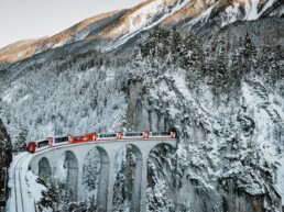 The Glacier Express crosses the landwasser viaduct at sunset in the winter
