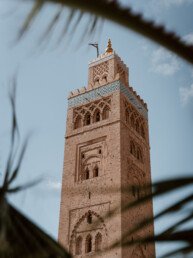 The Kutubiyya mosque in Marrakech with a palm tree leaf in the foreground