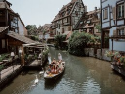 Wood boat with tourists on a small river in Colmar sailing between the houses